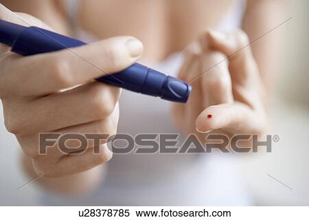 Stock Photography - Woman using lancelet on finger mid-section close up of finger. Fotosearch