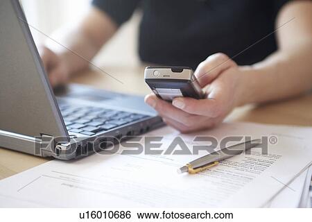Stock Photograph - Woman using laptop and mobile phone close up. Fotosearch