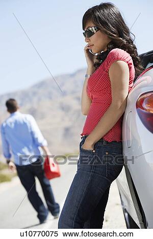 Woman using mobile phone leaning on out of gas car on desert roadside View Large Photo Image Stock Photography - Woman using mobile phone leaning on out of gas car on desert roadside. Fotosearch
