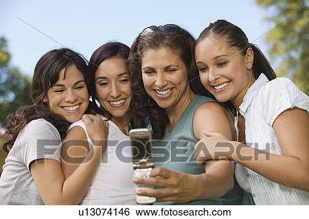 Woman using mobile phone photographing self with three women. View Large Photo Image Stock Photograph - Woman using mobile phone photographing self with three women.. Fotosearch