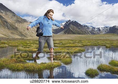 Woman walking barefoot through pond by mountains View Large Photo Image Picture - Woman walking barefoot through pond by mountains. Fotosearch