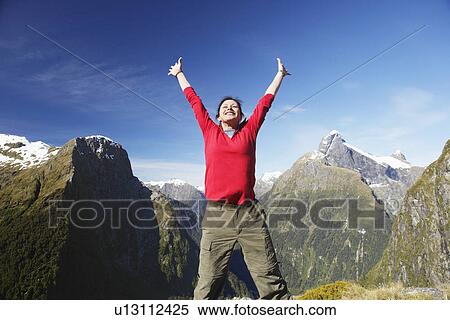 Woman with arms raised on top of mountain peak View Large Photo Image Stock Photography - Woman with arms raised on top of mountain peak. Fotosearch