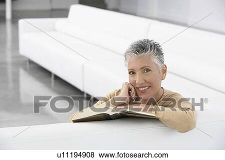 Woman with book on sofa smiling portrait View Large Photo Image Stock Photo - Woman with book on sofa smiling portrait. Fotosearch
