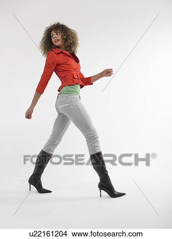 Picture - Woman with curly hair walking in studio. Fotosearch