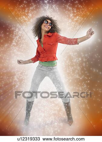 Stock Image - Woman with curly hair wearing sunglasses dancing with lighting effect. Fotosearch