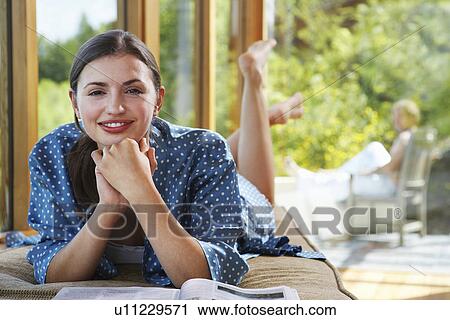 Woman with hands clasped to chin lying on front near windows overlooking forest View Large Photo Image Stock Image - Woman with hands clasped to chin lying on front near windows overlooking forest. Fotosearch