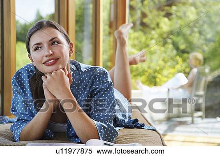 Woman with hands clasped to chin lying on front near windows overlooking forest View Large Photo Image Stock Photography - Woman with hands clasped to chin lying on front near windows overlooking forest. Fotosearch