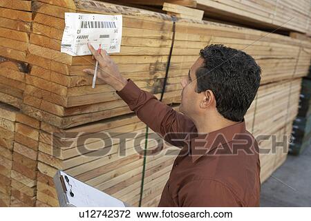 Worker checking label on stack of wood in warehouse head and shoulders View Large Photo Image Stock Image - Worker checking label on stack of wood in warehouse head and shoulders. Fotosearch
