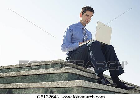 Young business man sitting on marble platform using laptop. View Large Photo Image Stock Image - Young business man sitting on marble platform using laptop.. Fotosearch