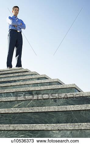 Young Business man standing at top of steps low angle portrait. View Large Photo Image Stock Image - Young Business man standing at top of steps low angle portrait.. Fotosearch
