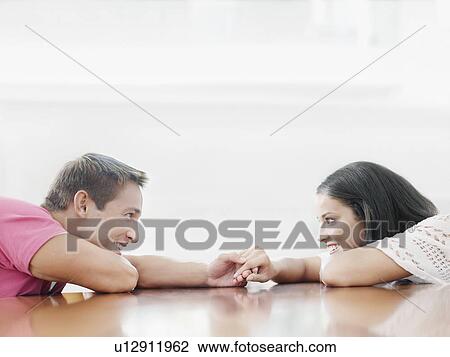 Young couple holding hands across table and looking into each other's eyes View Large Photo Image Stock Image - Young couple holding hands across table and looking into each other's eyes. Fotosearch
