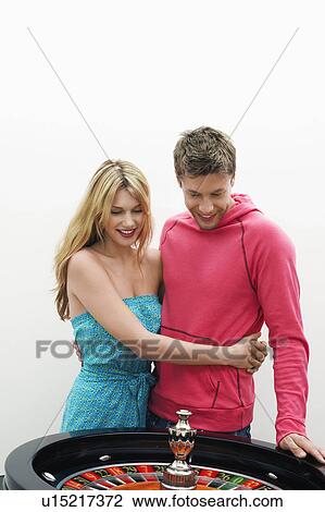 Stock Image - Young Couple hugging by roulette wheel. Fotosearch