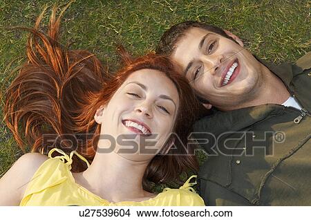 Picture - Young couple lying on grass portrait overhead view. Fotosearch