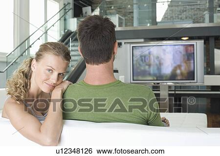 Young couple sitting on sofa View Large Photo Image Stock Photograph - Young couple sitting on sofa. Fotosearch