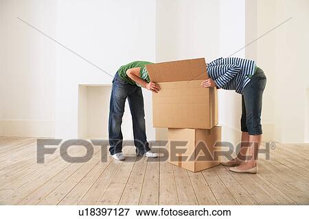 Stock Photo - Young couple unpacking box in new home with faces hidden. Fotosearch