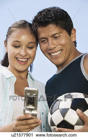 Young couple using mobile phone man holding soccer ball. View Large Photo Image Stock Image - Young couple using mobile phone man holding soccer ball.. Fotosearch