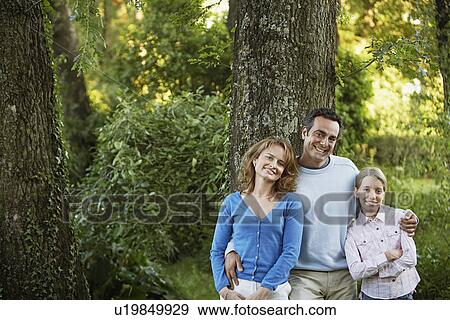 Young girl with parents leaning on tree in park portrait View Large Photo Image Stock Photo - Young girl with parents leaning on tree in park portrait. Fotosearch