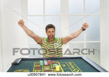Stock Image - Young Man celebrating on roulette table. Fotosearch