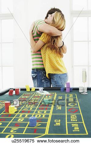 Stock Photography - Young man hugging woman at roulette table. Fotosearch