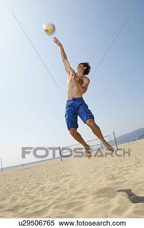 Young man jumping hitting volleyball on beach View Large Photo Image Stock Photography - Young man jumping hitting volleyball on beach. Fotosearch