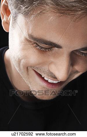 Stock Image - Young Man looking down smiling. Fotosearch