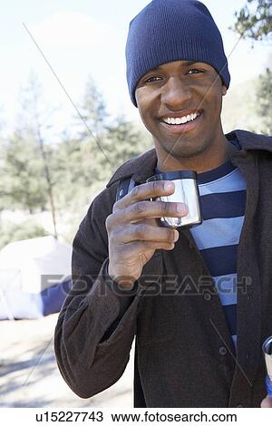 Young man standing at campsite with mug in hand half length View Large Photo Image Stock Image - Young man standing at campsite with mug in hand half length. Fotosearch