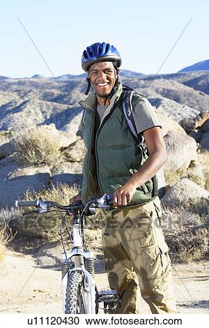 Young man standing with mountain bike in front of hills View Large Photo Image Stock Image - Young man standing with mountain bike in front of hills. Fotosearch