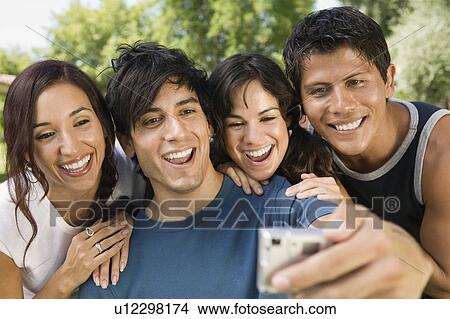 Young man using digital camera photographing self with three friends. View Large Photo Image Picture - Young man using digital camera photographing self with three friends.. Fotosearch