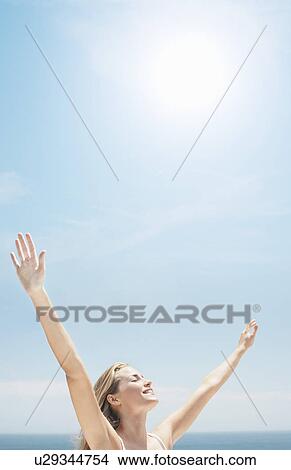 Young woman at seashore with raised arms View Large Photo Image Picture - Young woman at seashore with raised arms. Fotosearch