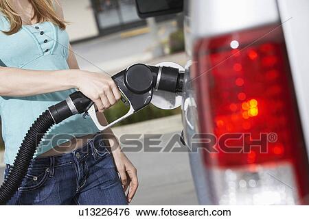 Young woman filling car with gas at gas station mid section View Large Photo Image Stock Photograph - Young woman filling car with gas at gas station mid section. Fotosearch