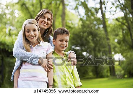 Stock Photograph - Young Woman Hugging Children in back yard portrait. Fotosearch