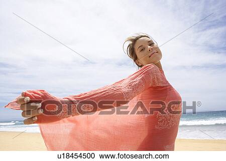 Stock Image - Young woman in shawl on beach side view. Fotosearch