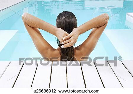 Young Woman in Swimming Pool at poolside pulling back hair back view View Large Photo Image Stock Image - Young Woman in Swimming Pool at poolside pulling back hair back view. Fotosearch
