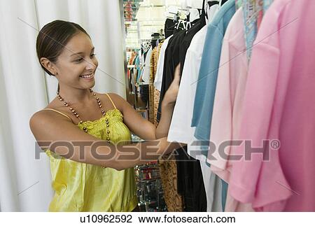 Young Woman Looking Through Clothing Rack in store View Large Photo Image Stock Image - Young Woman Looking Through Clothing Rack in store. Fotosearch
