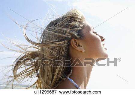 Young woman on beach with wind-swept hair close up side view head shot View Large Photo Image Stock Photo - Young woman on beach with wind-swept hair close up side view head shot. Fotosearch