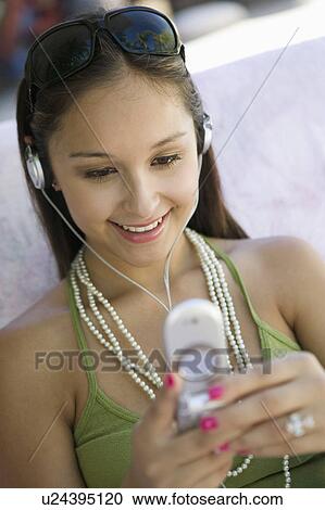Young woman on sofa sending text message and listening to music on headphones View Large Photo Image Stock Image - Young woman on sofa sending text message and listening to music on headphones. Fotosearch