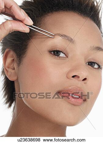 Stock Photo - Young Woman plucking Eyebrows close up head shot. Fotosearch