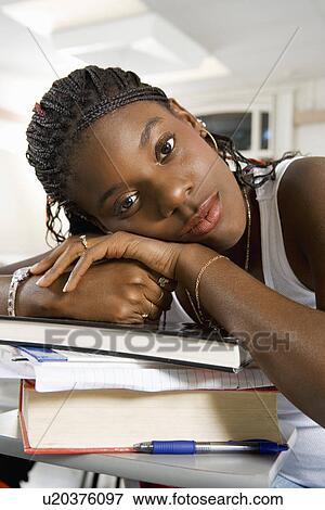 Young woman resting on stacked books (close-up) (portrait) View Large Photo Image Stock Photo - Young woman resting on stacked books (close-up) (portrait). Fotosearch