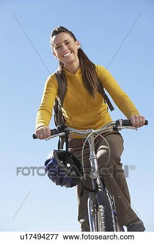 Stock Photo - Young woman riding mountain bike low angle view.. Fotosearch