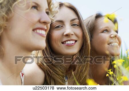 Young woman sitting with friends in flowery field portrait selective focus View Large Photo Image Stock Photo - Young woman sitting with friends in flowery field portrait selective focus. Fotosearch