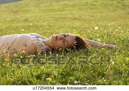 Picture - Young woman sleeping in field ground view. Fotosearch