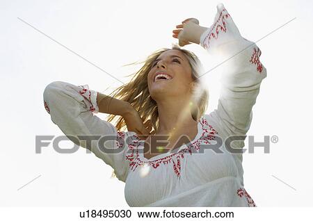 Stock Image - Young woman smiling portrait low angle view. Fotosearch