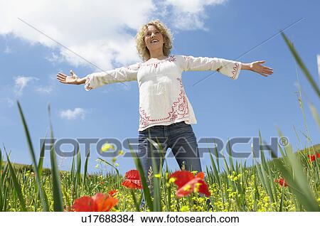 Young woman standing in field with open arms low angle view front view View Large Photo Image Picture - Young woman standing in field with open arms low angle view front view. Fotosearch