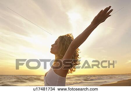 Young woman stretching on beach with eyes closed side view View Large Photo Image Picture - Young woman stretching on beach with eyes closed side view. Fotosearch