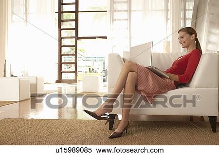 Young woman using laptop in living room View Large Photo Image Stock Photography - Young woman using laptop in living room. Fotosearch