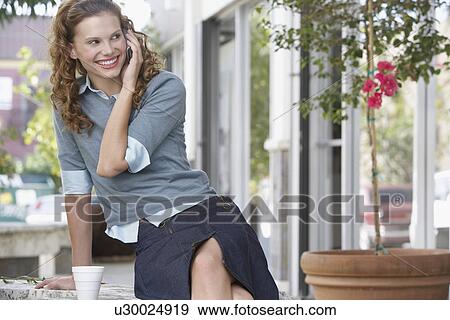 Stock Photo - Young woman using mobile phone outdoors. Fotosearch