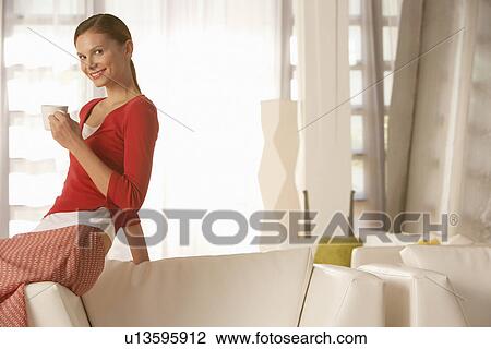 Young woman with drink in living room portrait View Large Photo Image Stock Image - Young woman with drink in living room portrait. Fotosearch