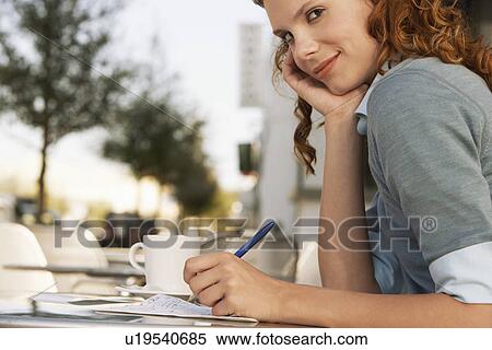 Stock Photography - Young woman writing at outdoor cafe close-up. Fotosearch