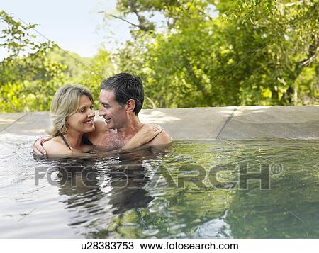 Stock Image - Adult couple embracing in pool smiling. Fotosearch