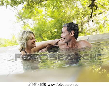 Stock Photo - Adult couple embracing in pool smiling. Fotosearch
